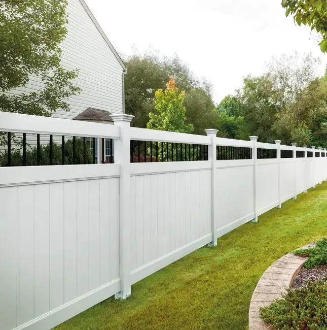 A white vinyl fence with a black railing is in front of a house in Westerville