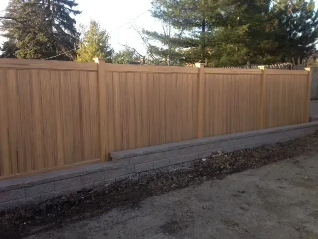 A wooden vinyl fence is surrounded by trees in a backyard in Columbus