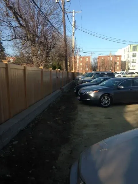 A row of cars parked next to a wooden vinyl fence in Columbus
