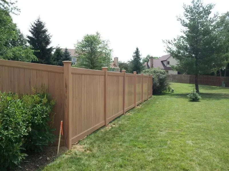 A wooden vinly fence surrounds a lush green yard in Columbus