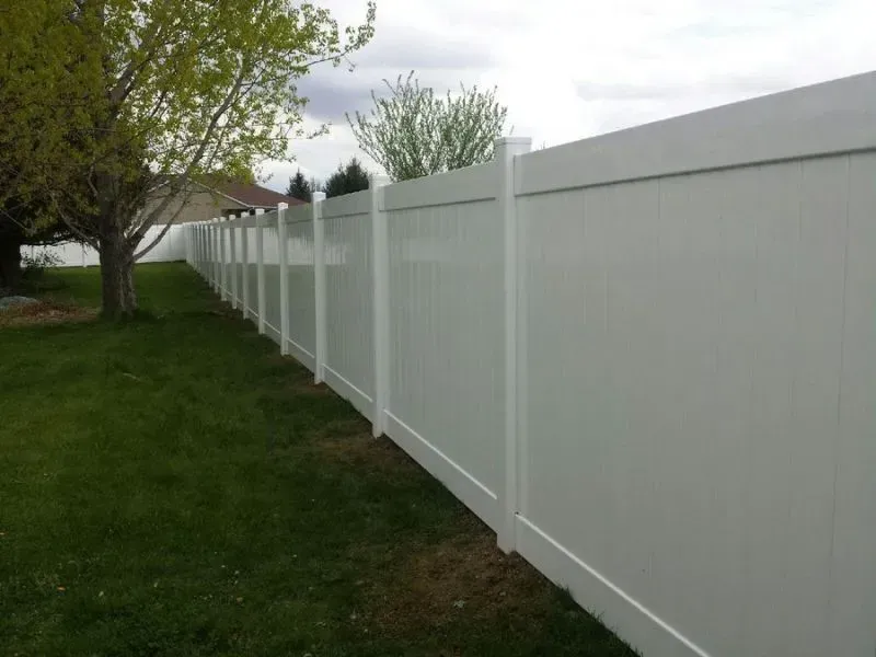 A white vinyl fence surrounds a lush green yard in Columbus