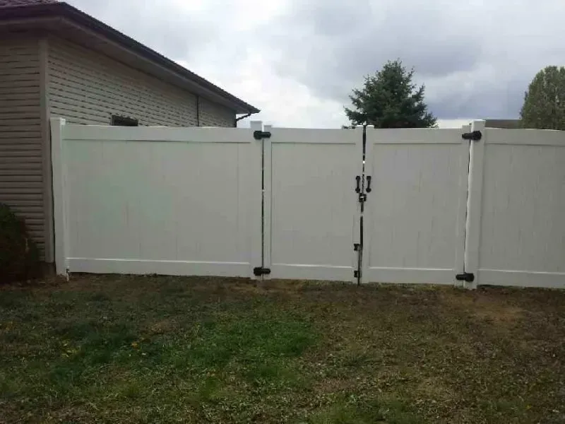 A white vinyl fence with a gate in the backyard of a house in Columbus