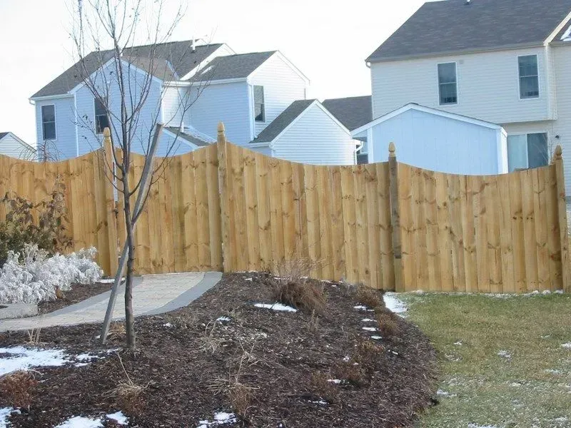 A wooden fence surrounds a yard with houses in the background in Columbus