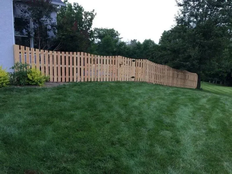 A wooden fence surrounds a lush green lawn in front of a house in Columbus