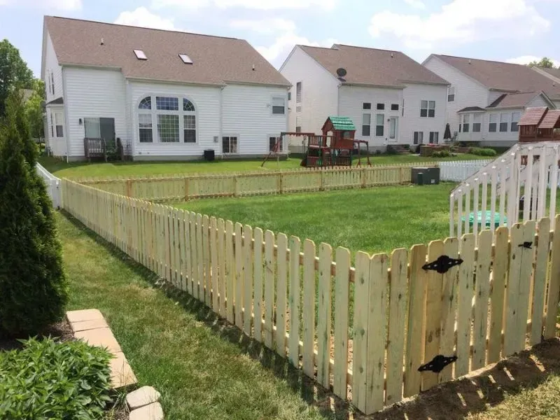 A wooden picket fence surrounds a lush green yard in front of a house in Galena