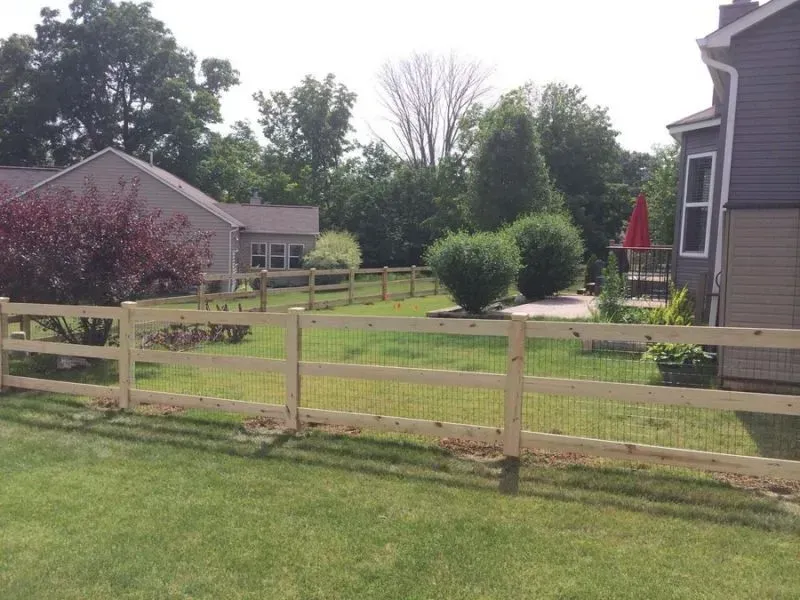 A wooden fence surrounds a lush green yard in front of a house in Columbus