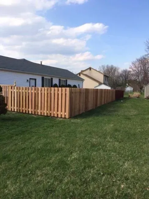 A wooden fence surrounds a lush green yard in front of a house in Columbus