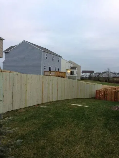 A wooden fence surrounds a lush green yard in front of a house in Columbus