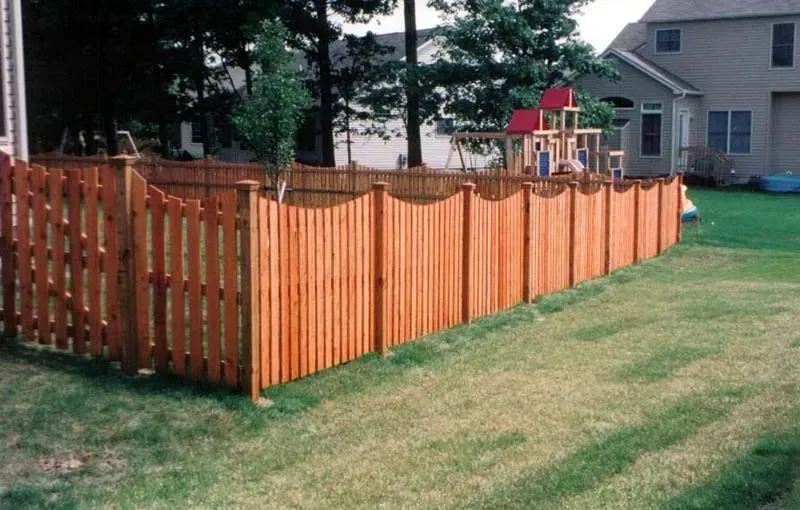 A wooden fence in a backyard with a playground in the background in Galena