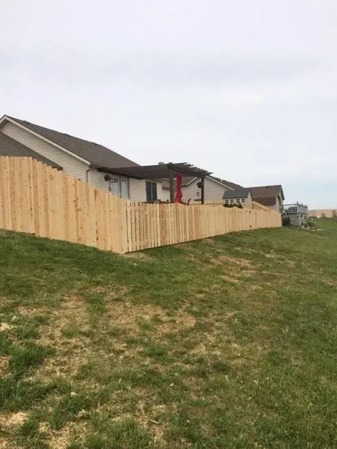 A wooden fence surrounds a grassy field in front of a house in Columbus