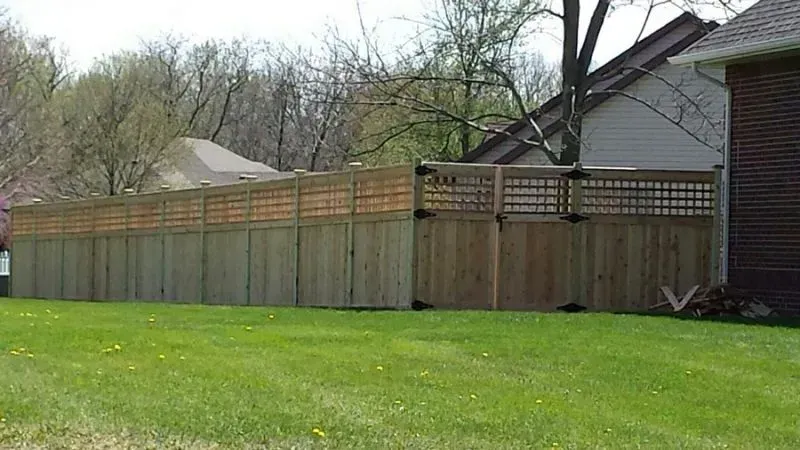 A wooden fence surrounds a lush green yard in front of a house in Grove City