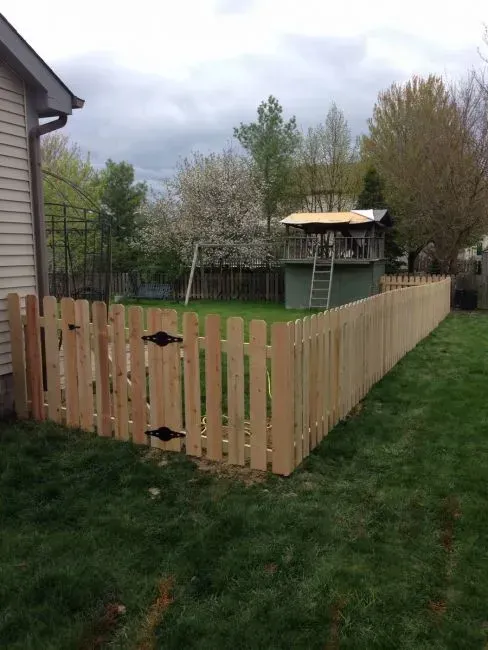 A wooden fence surrounds a backyard with a house in the background in Columbus