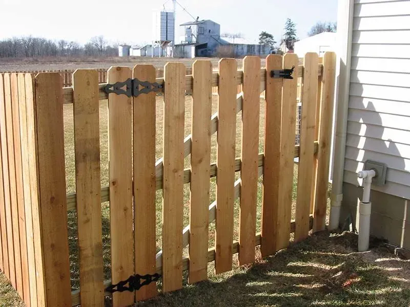 A wooden fence is next to a white house in Columbus