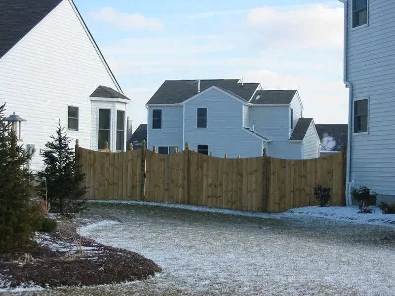 A wooden fence surrounds a driveway between two houses in Columbus
