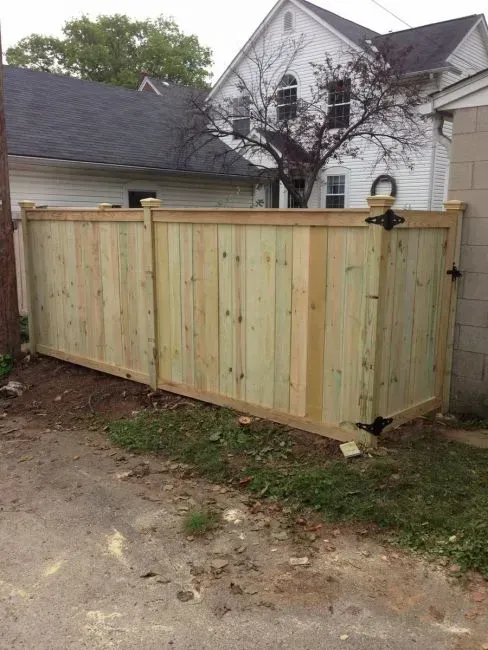 A wooden fence is sitting in front of a white house in Columbus