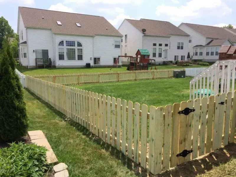 A wooden fence surrounds a lush green yard in front of a house in Columbus