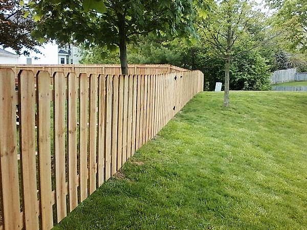 A wooden fence surrounds a lush green lawn in a backyard in Powell
