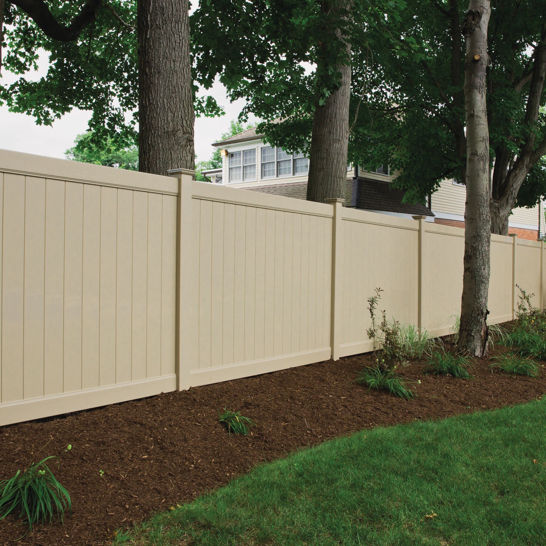A tan fence with dogwood trees in the background in Lewis Center.