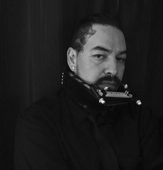 A black and white photo of a man with a harmonica in his mouth.