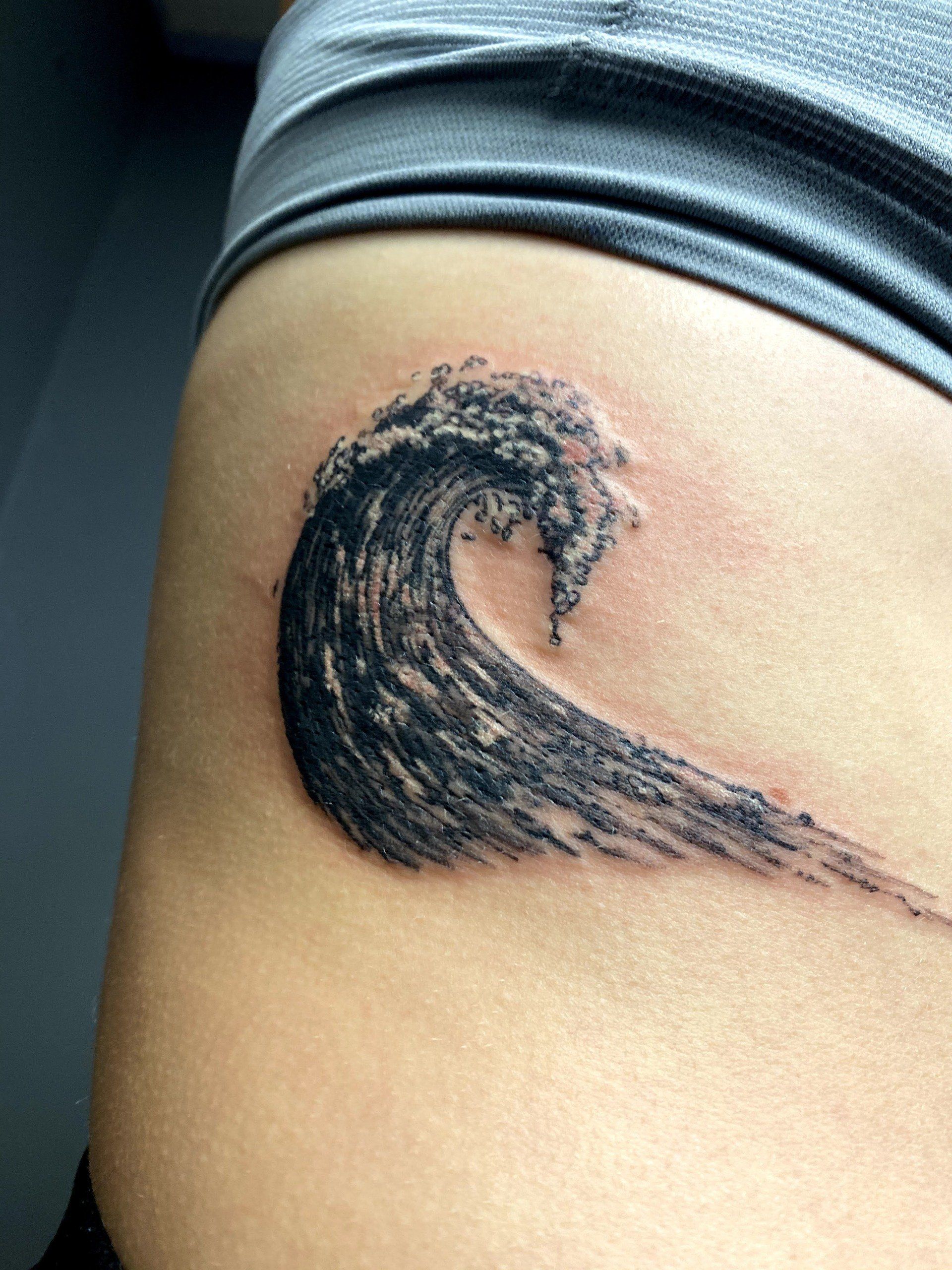 A person has a tattoo of a wave on their side.