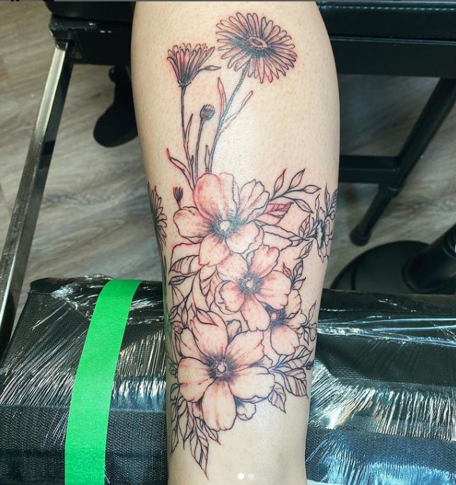 A woman has a tattoo of flowers on her leg