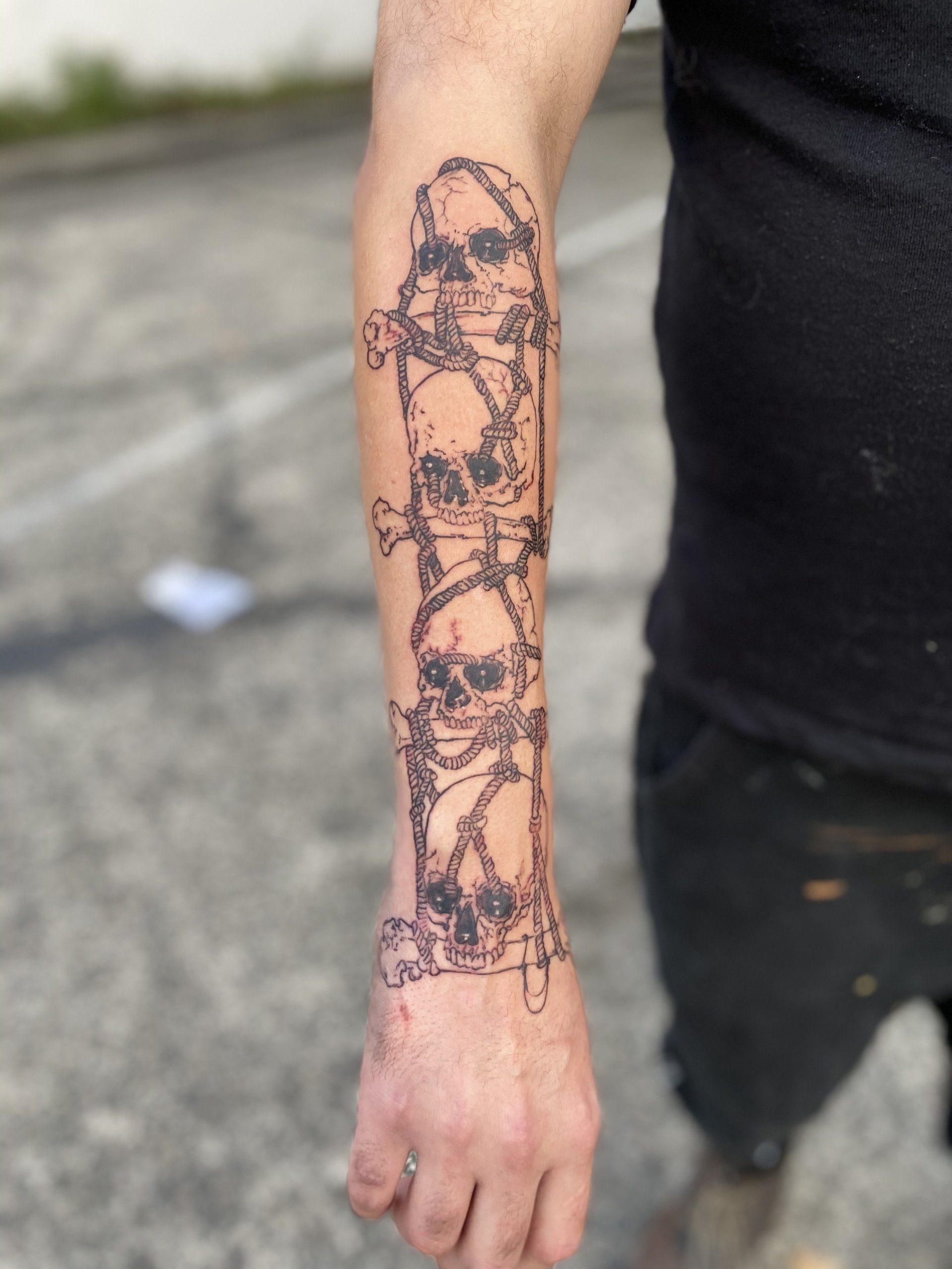 A man has a tattoo of four skulls on his forearm