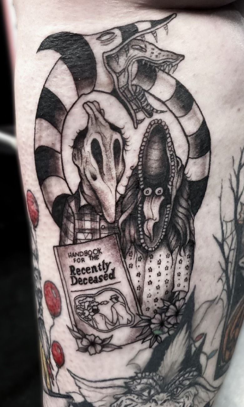 A black and white tattoo of a skeleton holding a book.