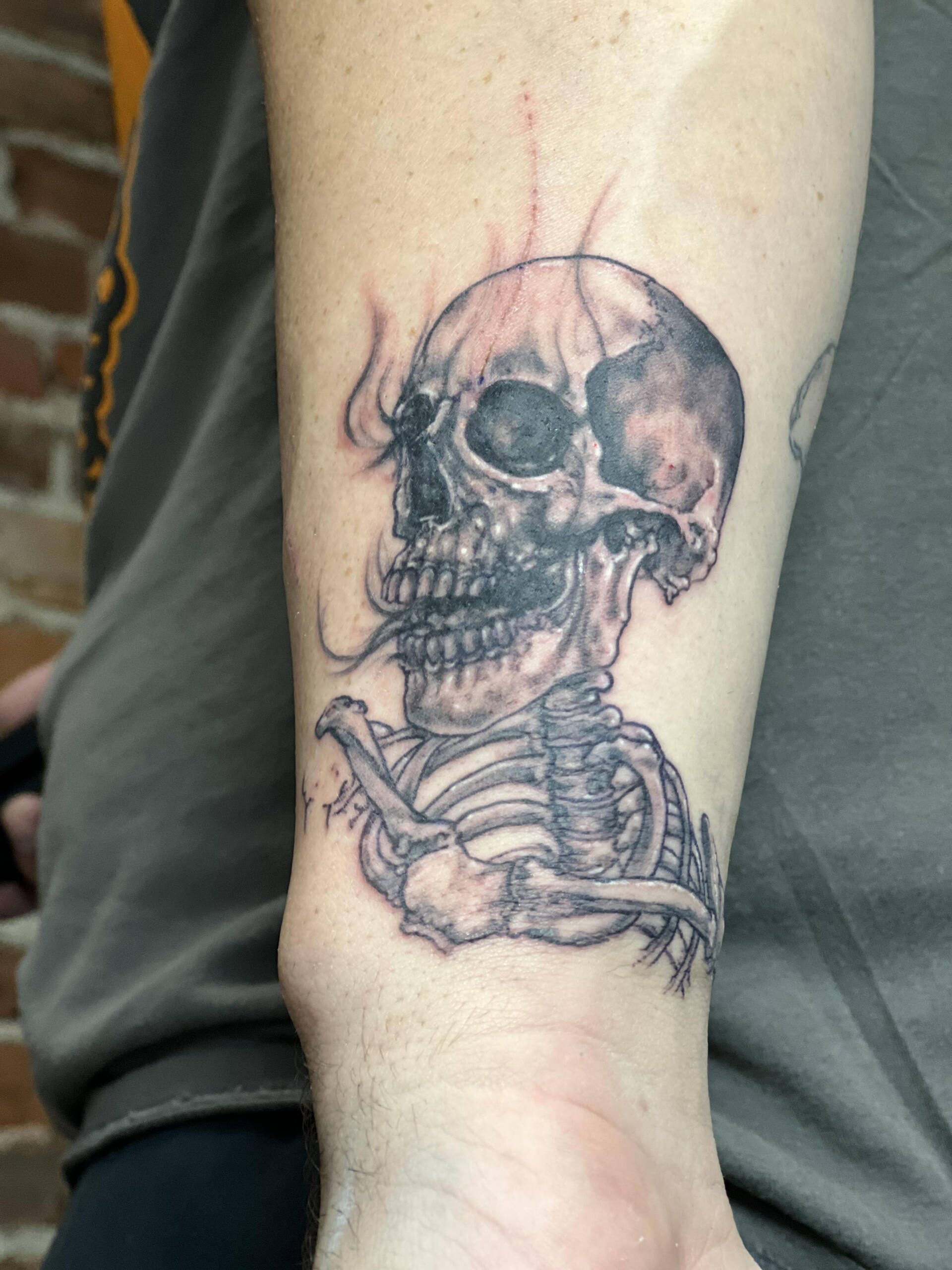 A tattoo of a skeleton with flames coming out of its mouth