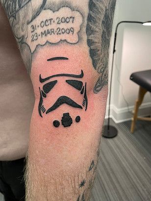 A man has a storm trooper tattoo on his elbow.