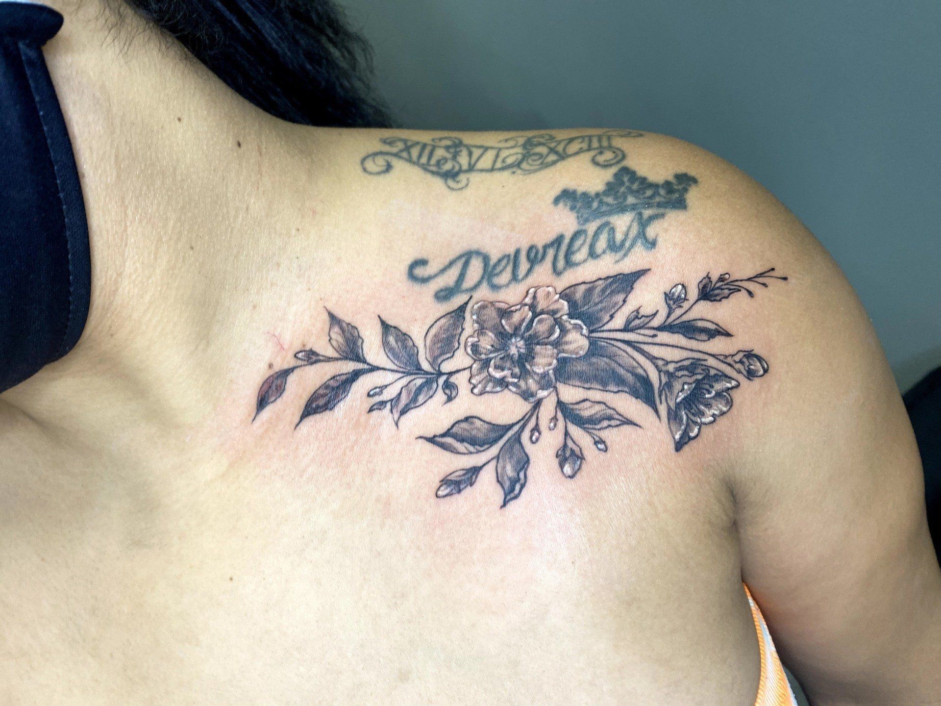 A woman has a tattoo on her shoulder that says devineat