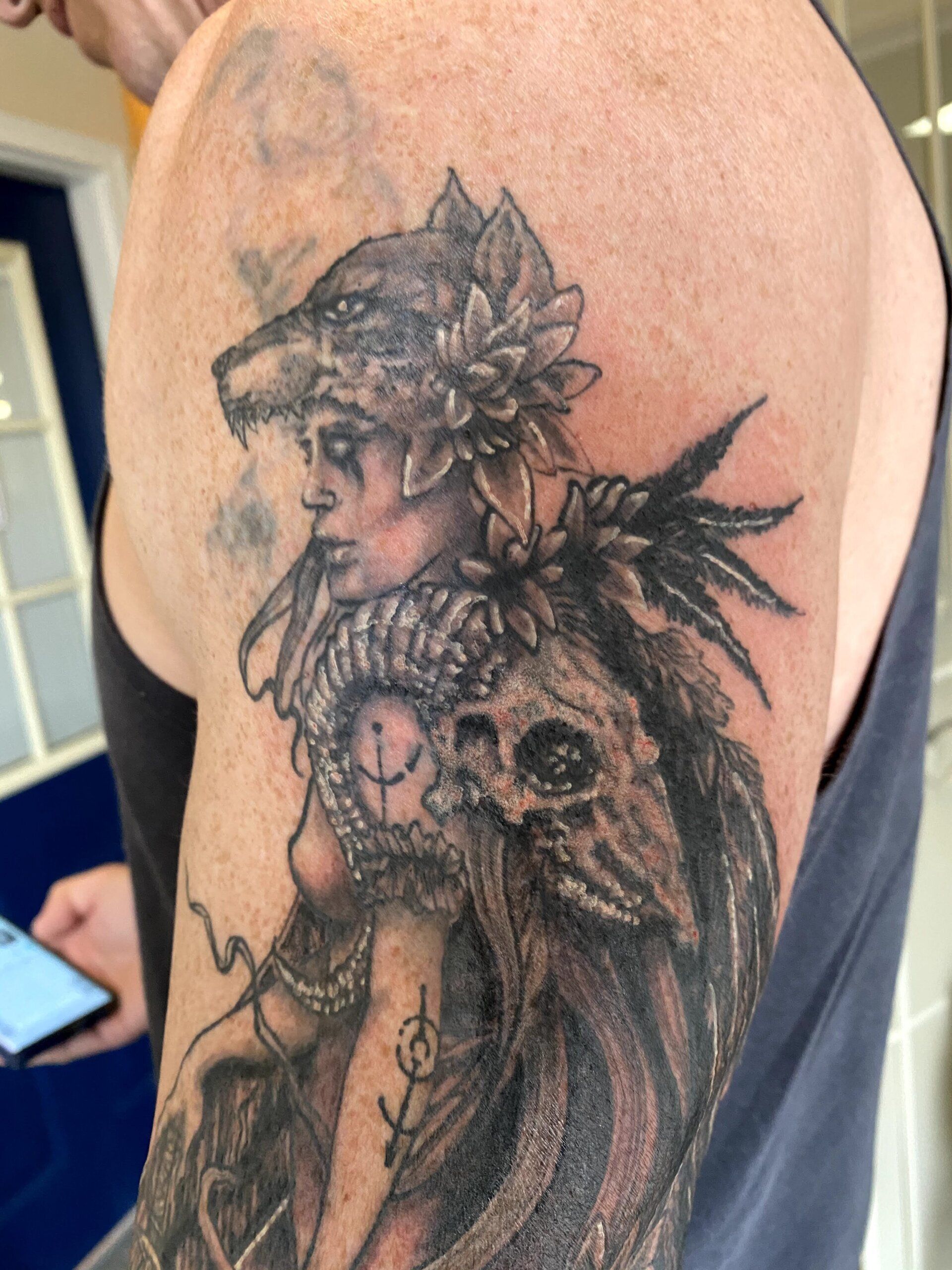 A man has a tattoo of a woman with a wolf on her head