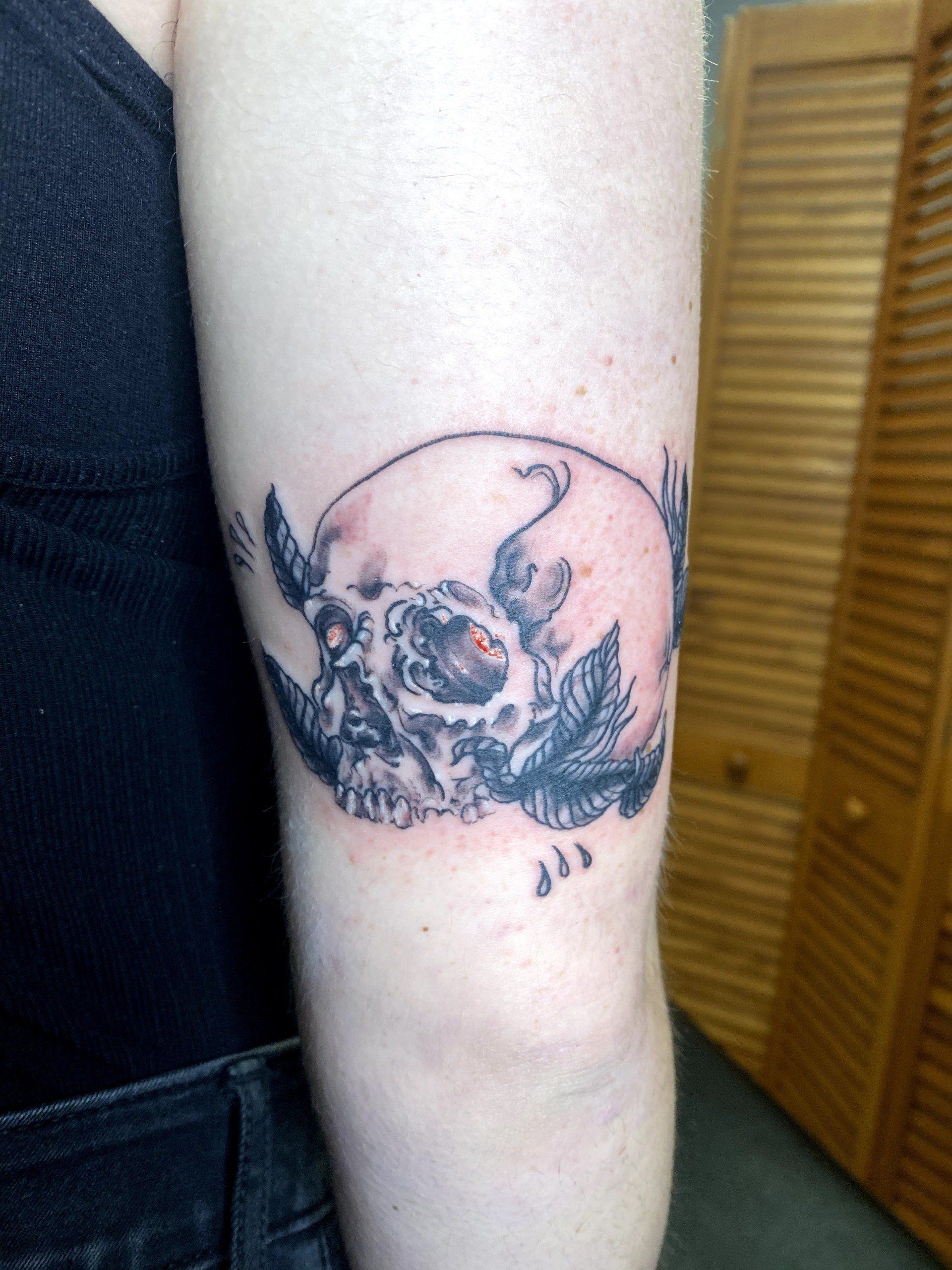 A woman has a tattoo of a skull on her arm