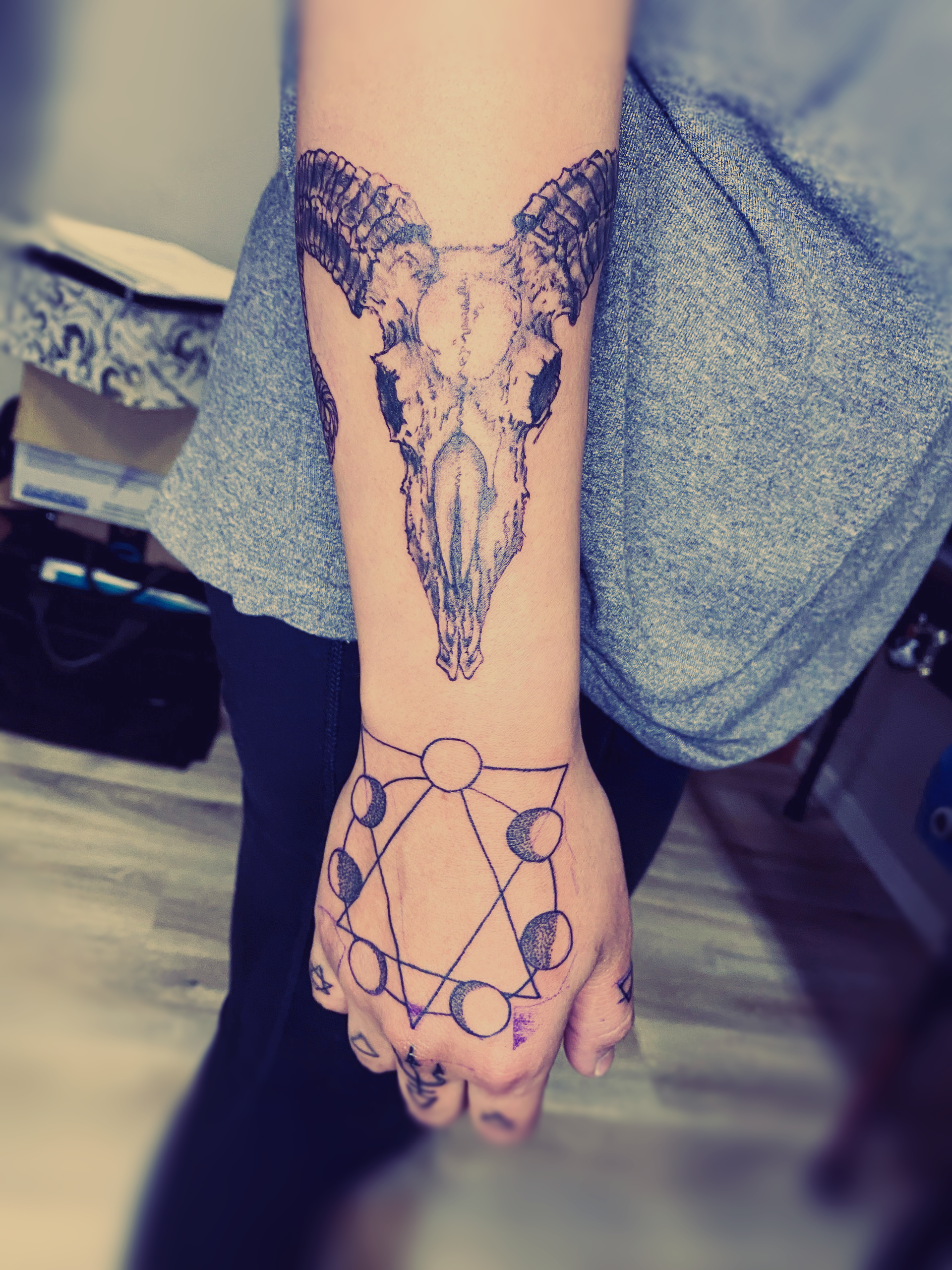 A person has a tattoo of a ram skull on their wrist