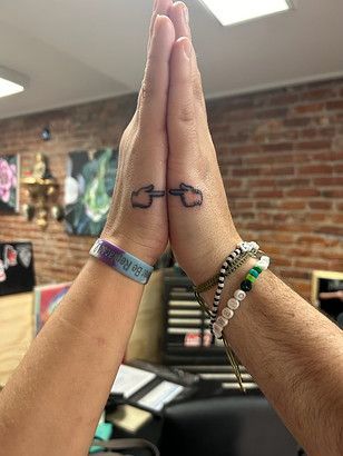 A person with a tattoo on their wrist is giving each other a high five.