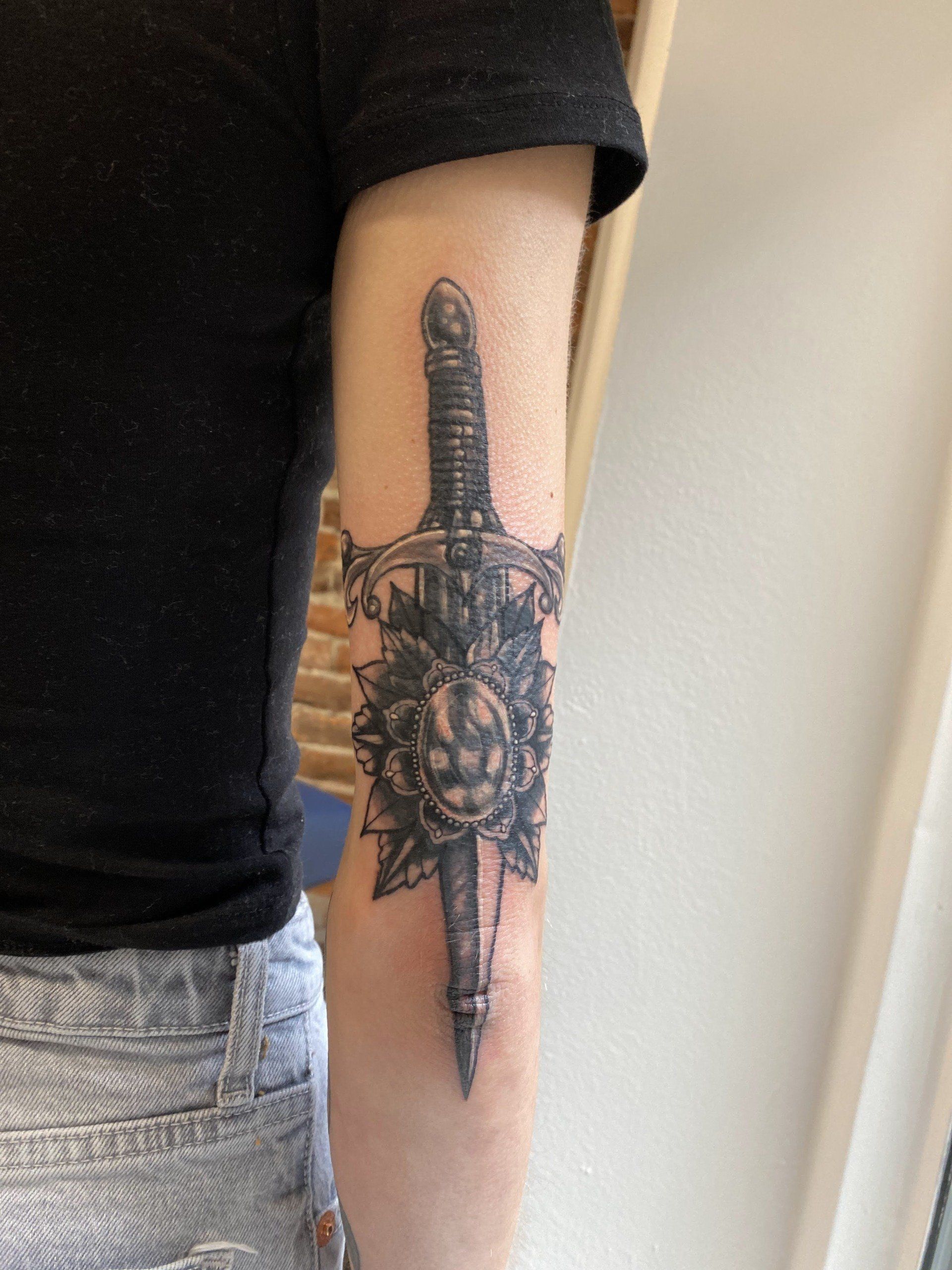 black and grey tattoo of sword and flower