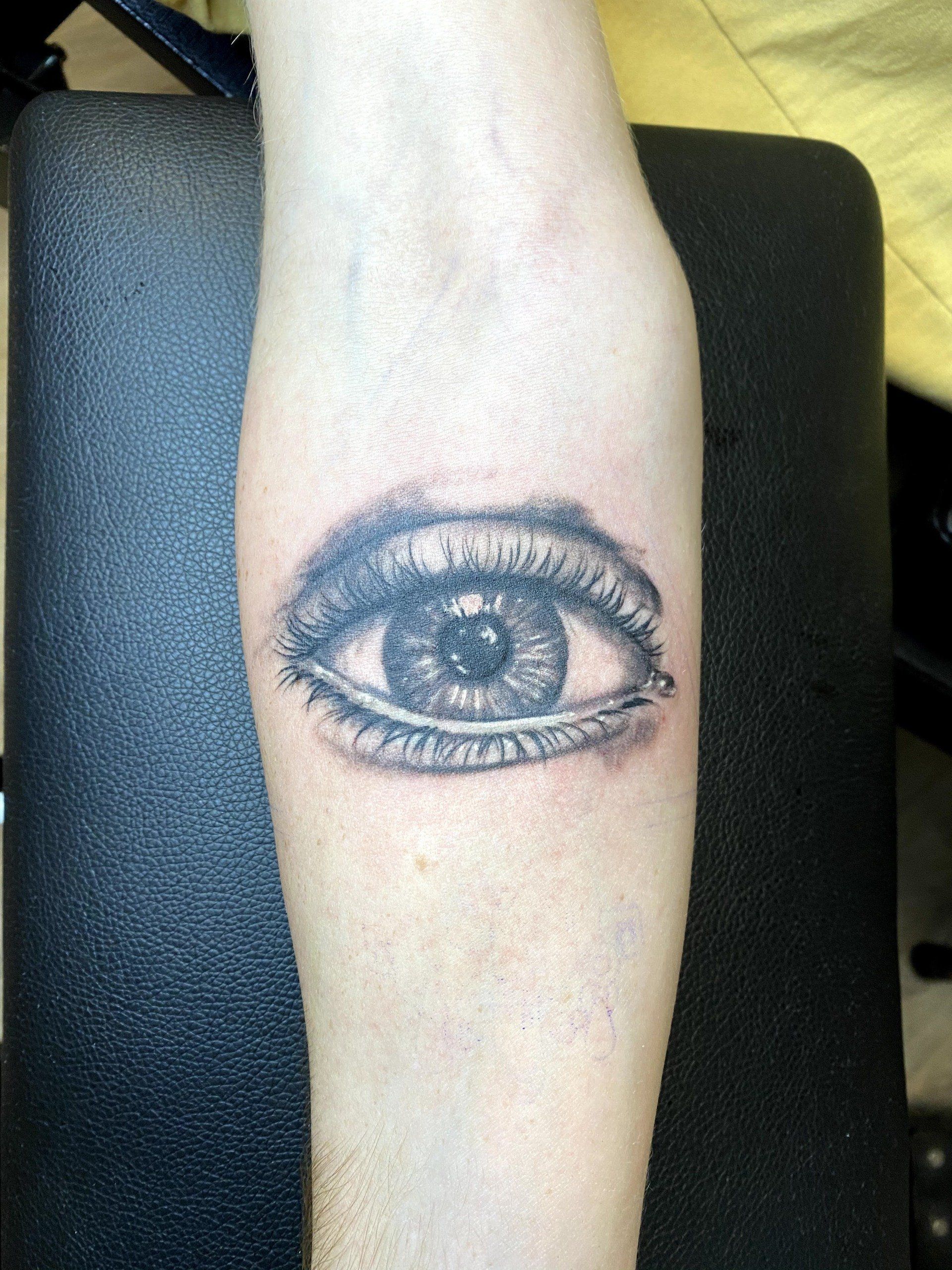 A person has a tattoo of an eye on their forearm
