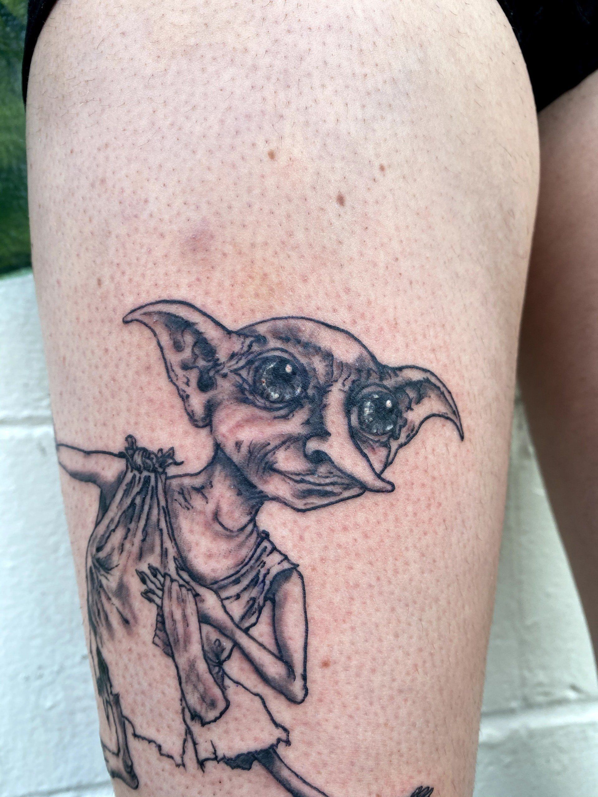 A person has a tattoo of a dobby on their leg