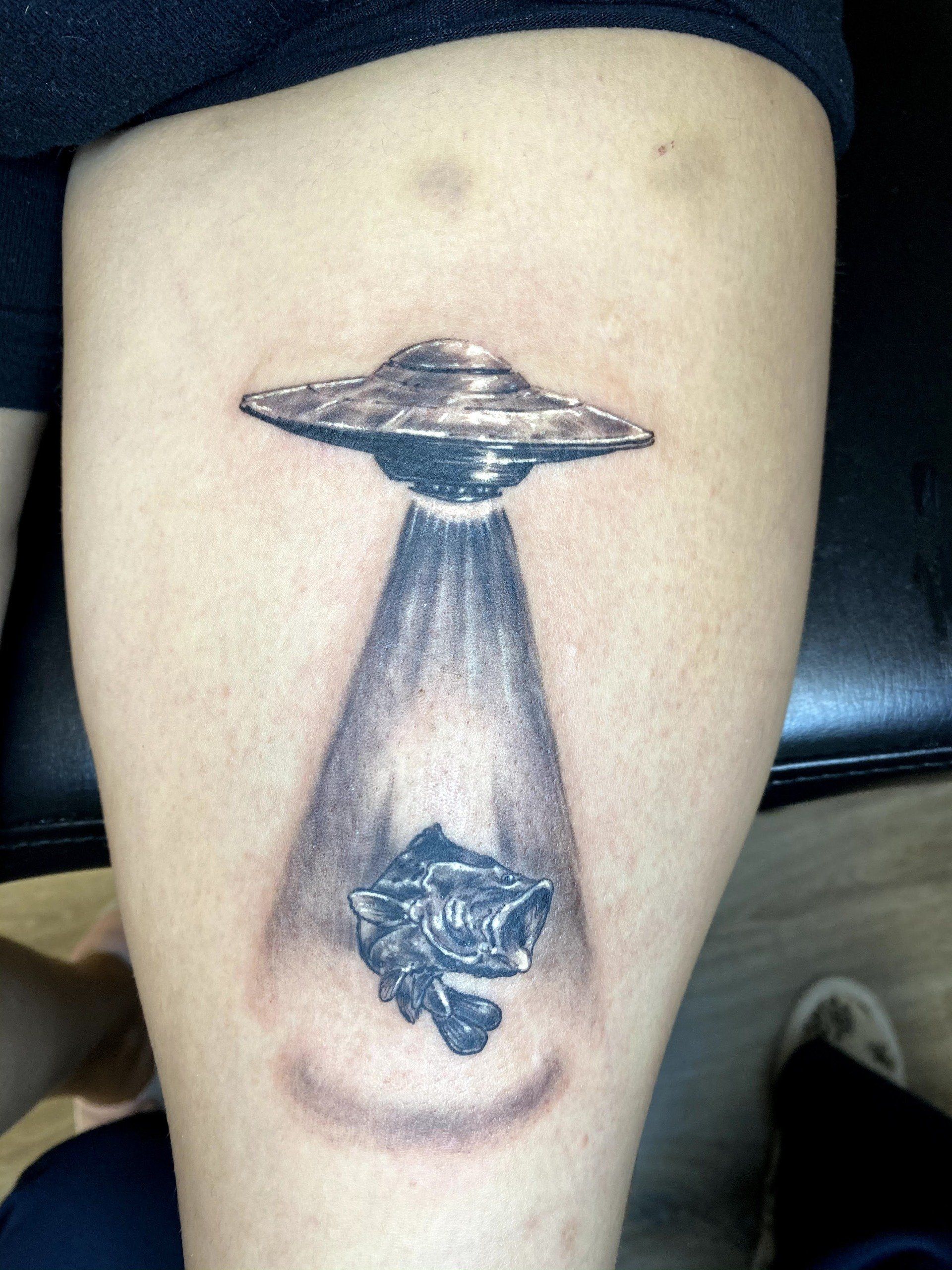 A tattoo on a person 's leg shows an alien flying saucer