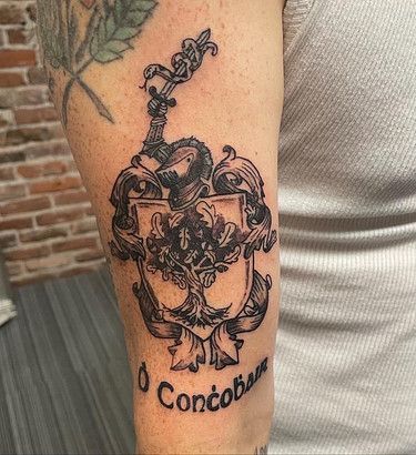 A person has a tattoo of a coat of arms on their arm.
