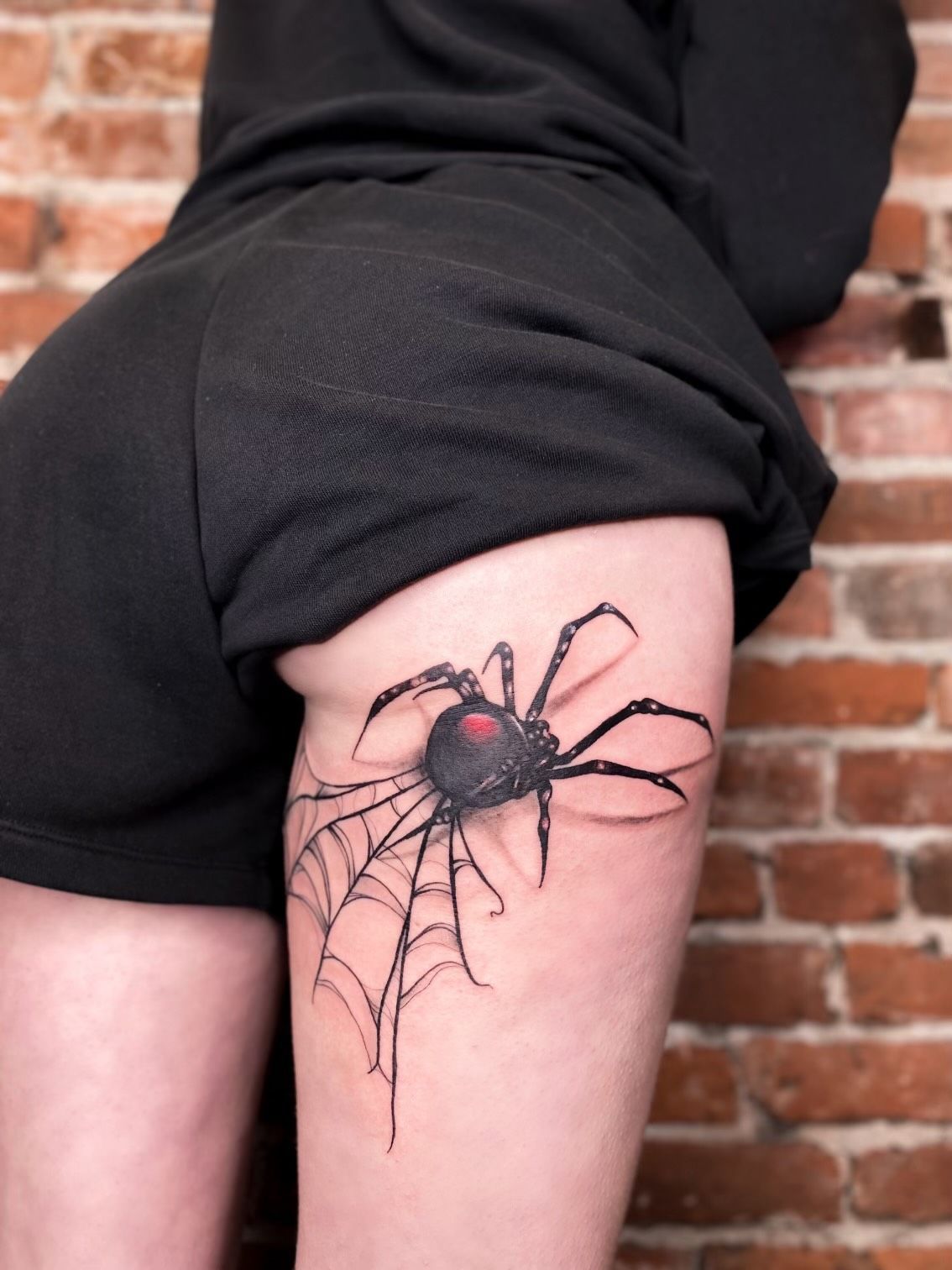 A woman has a tattoo of a spider on her thigh