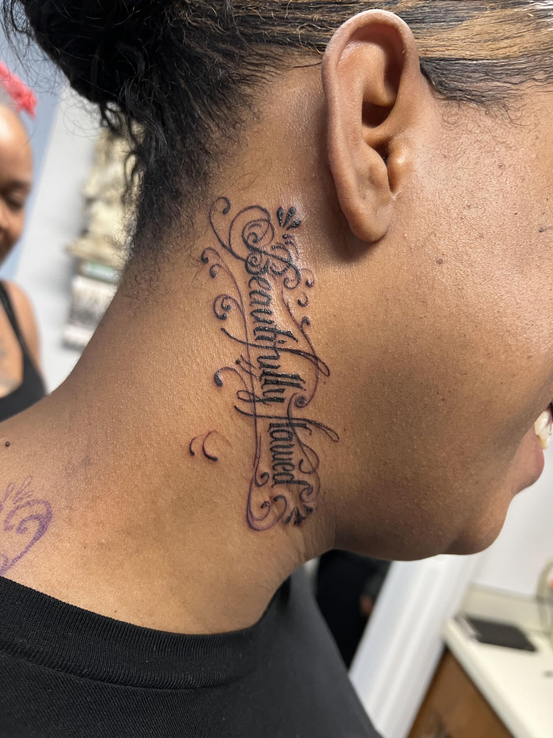 A woman has a tattoo on her neck that says beautifully blessed