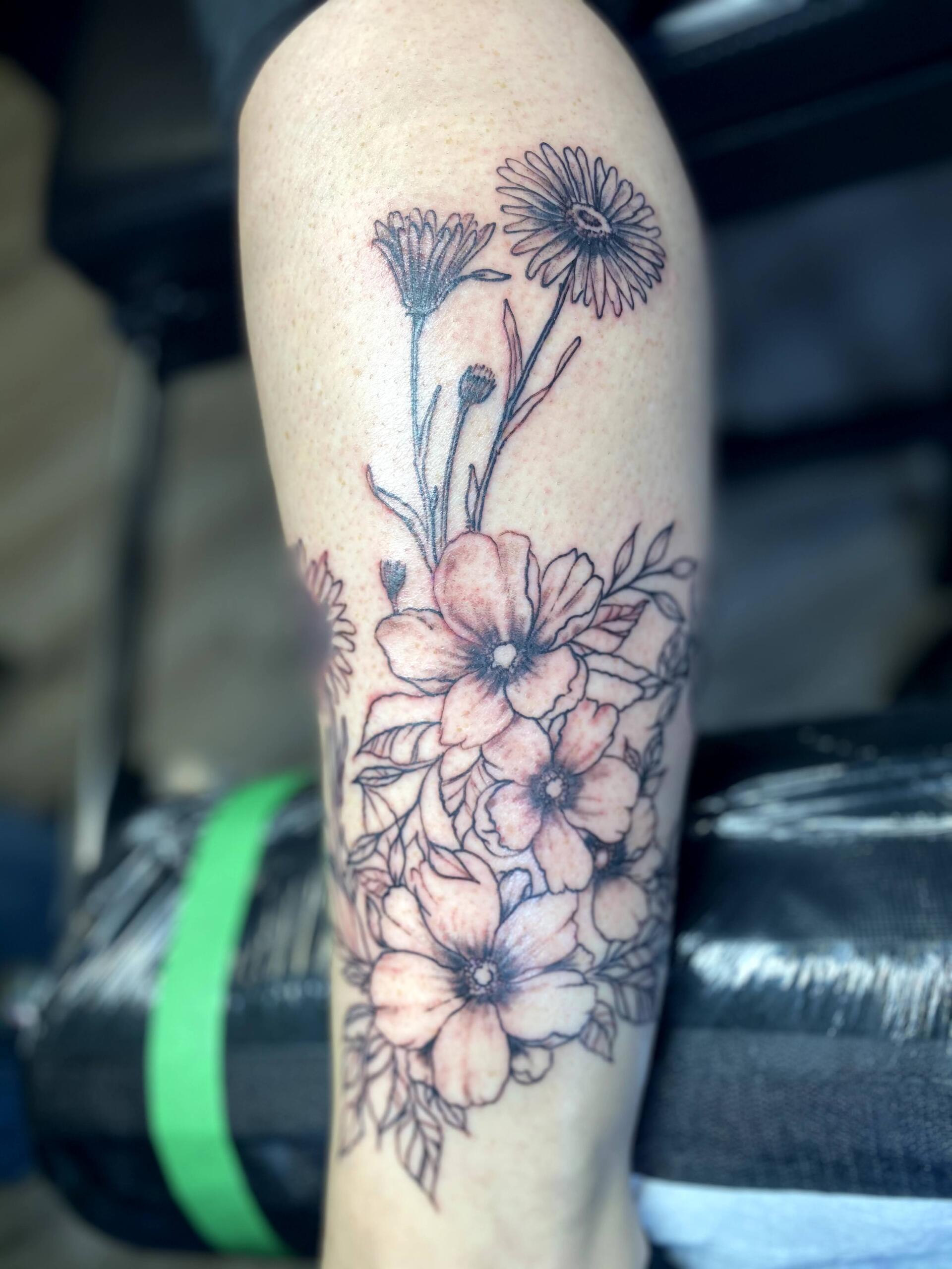 A woman has a tattoo of flowers on her leg