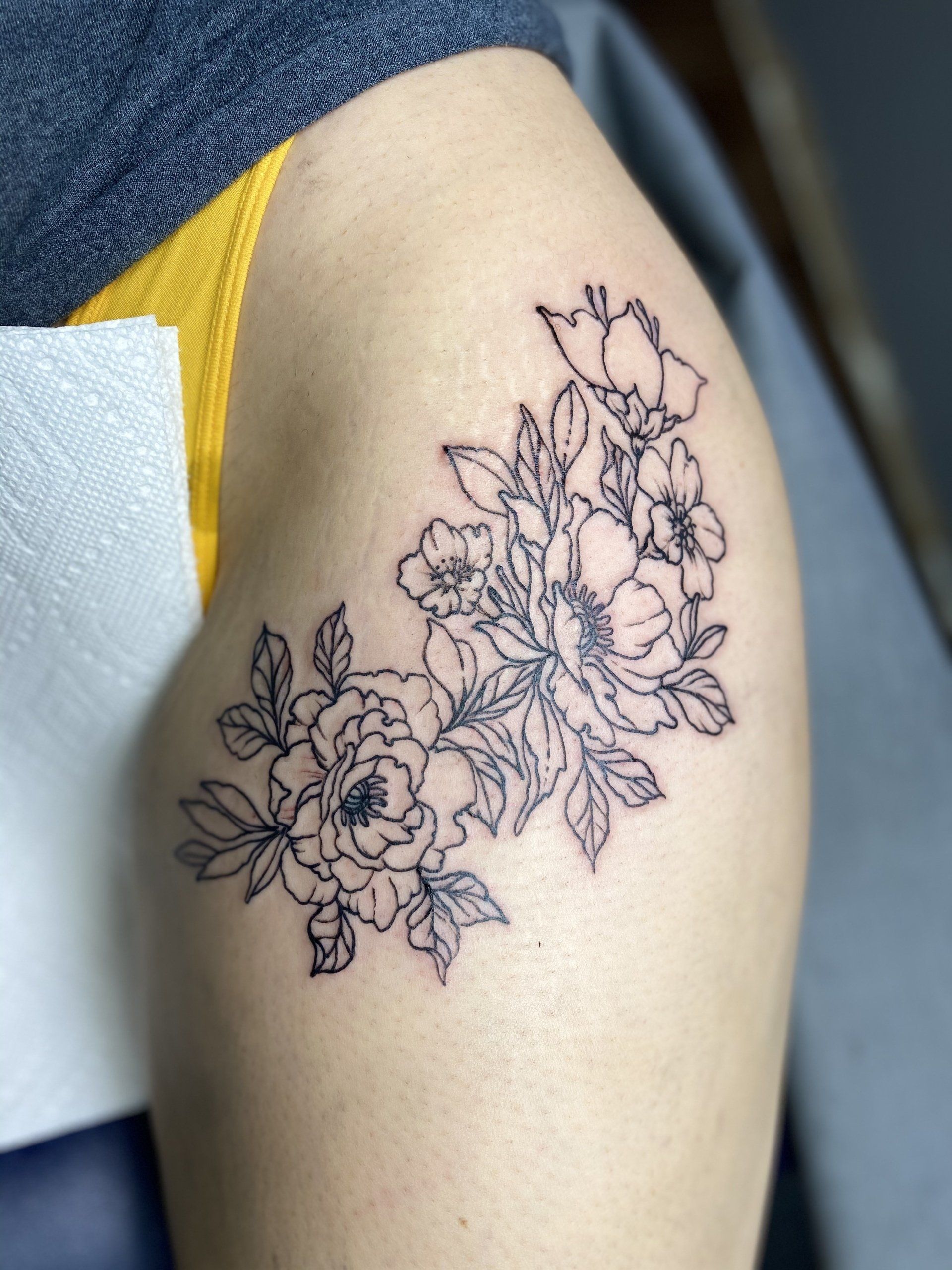 A woman has a tattoo of flowers on her thigh