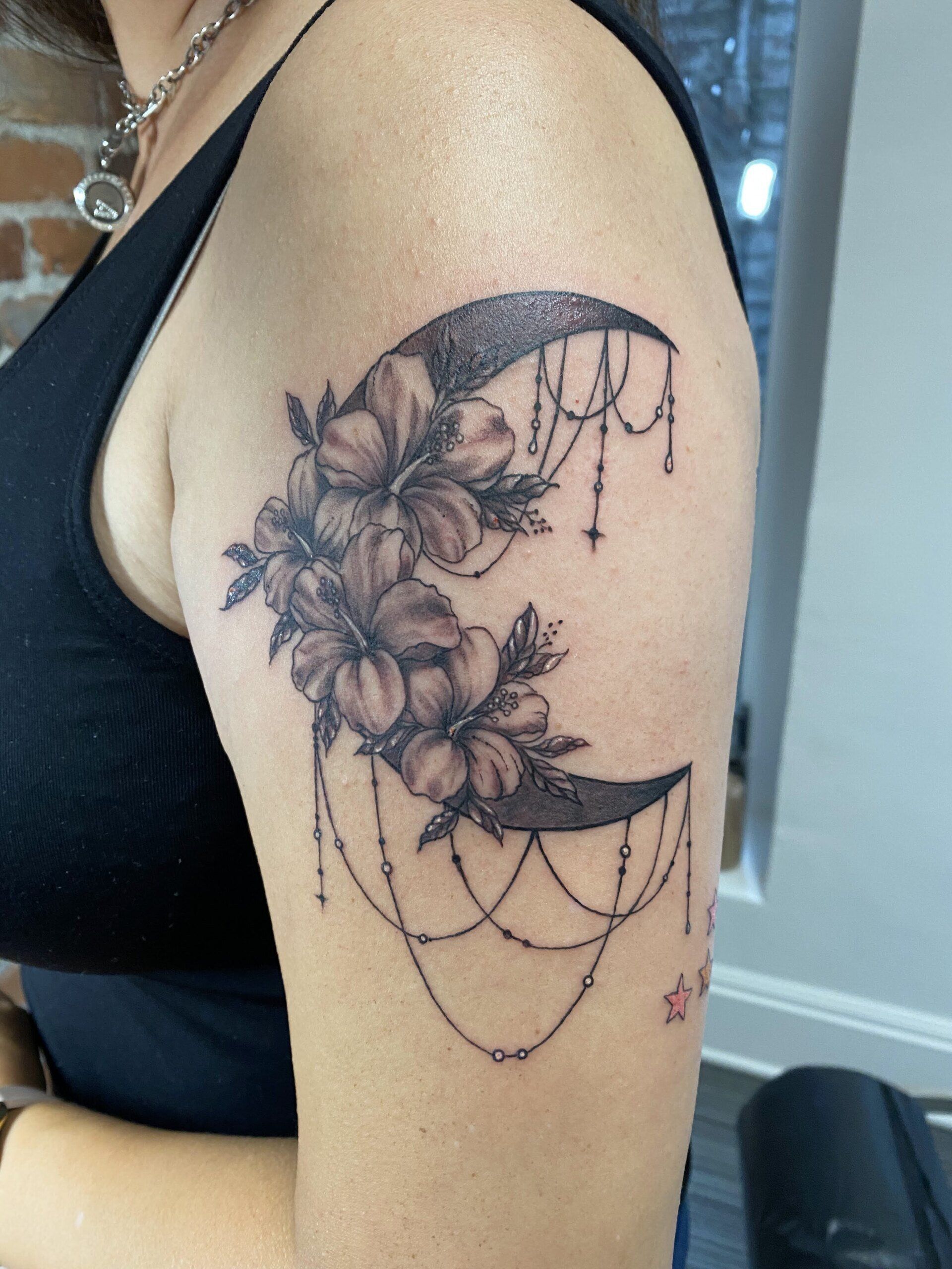 A woman has a tattoo of a crescent moon with flowers on it