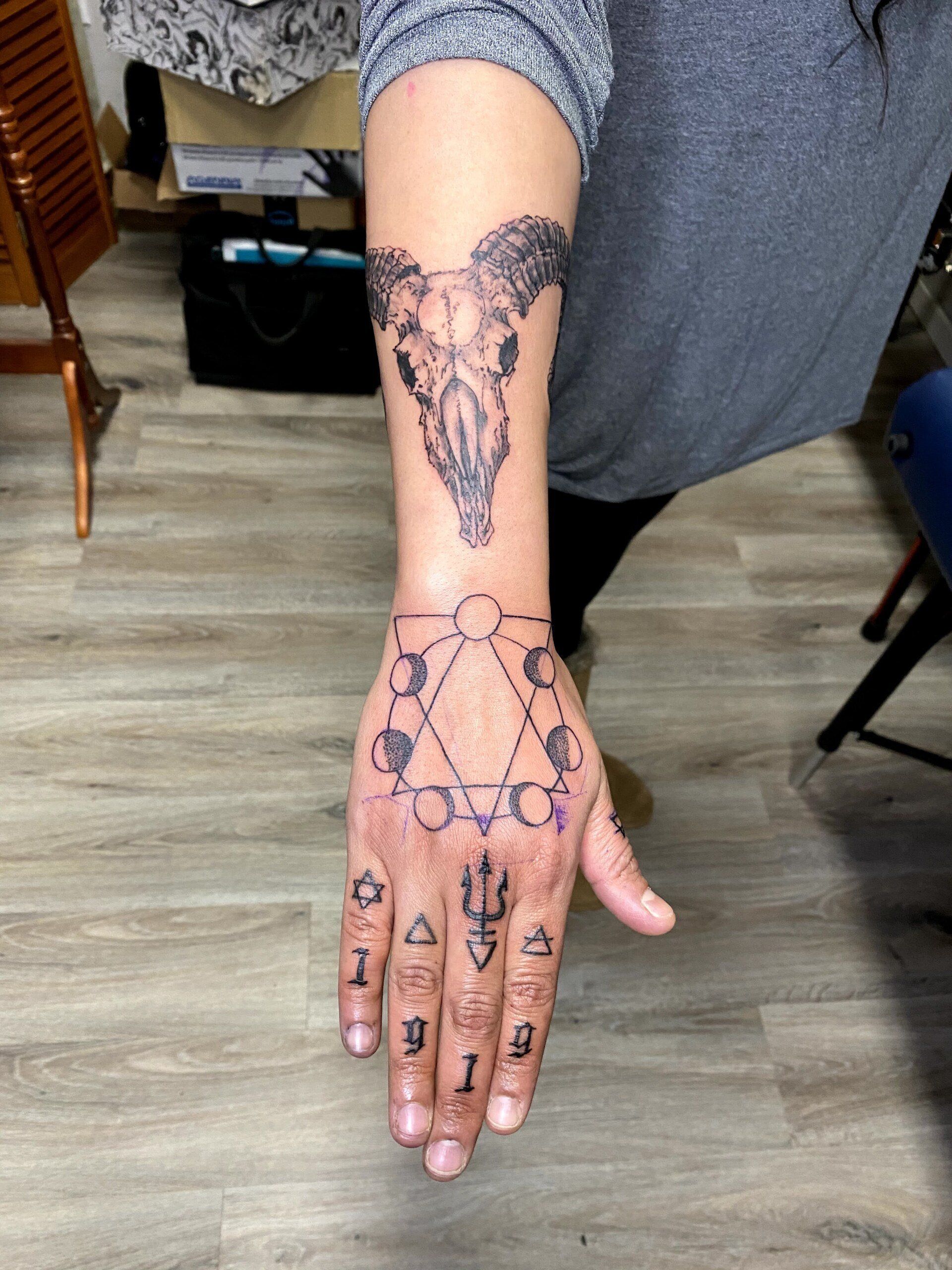 A woman has a tattoo of a ram skull on her hand