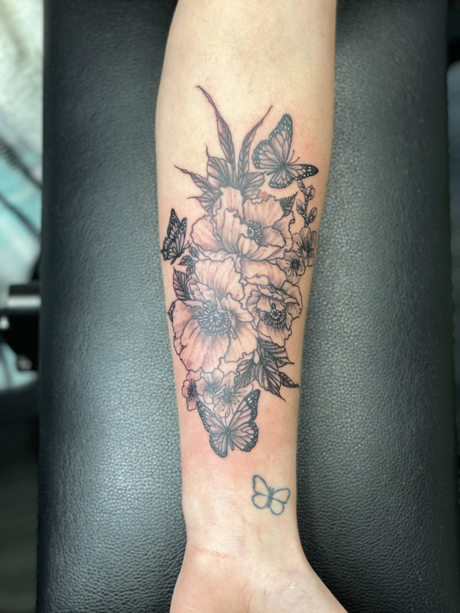 A tattoo of flowers and butterflies on a person 's forearm