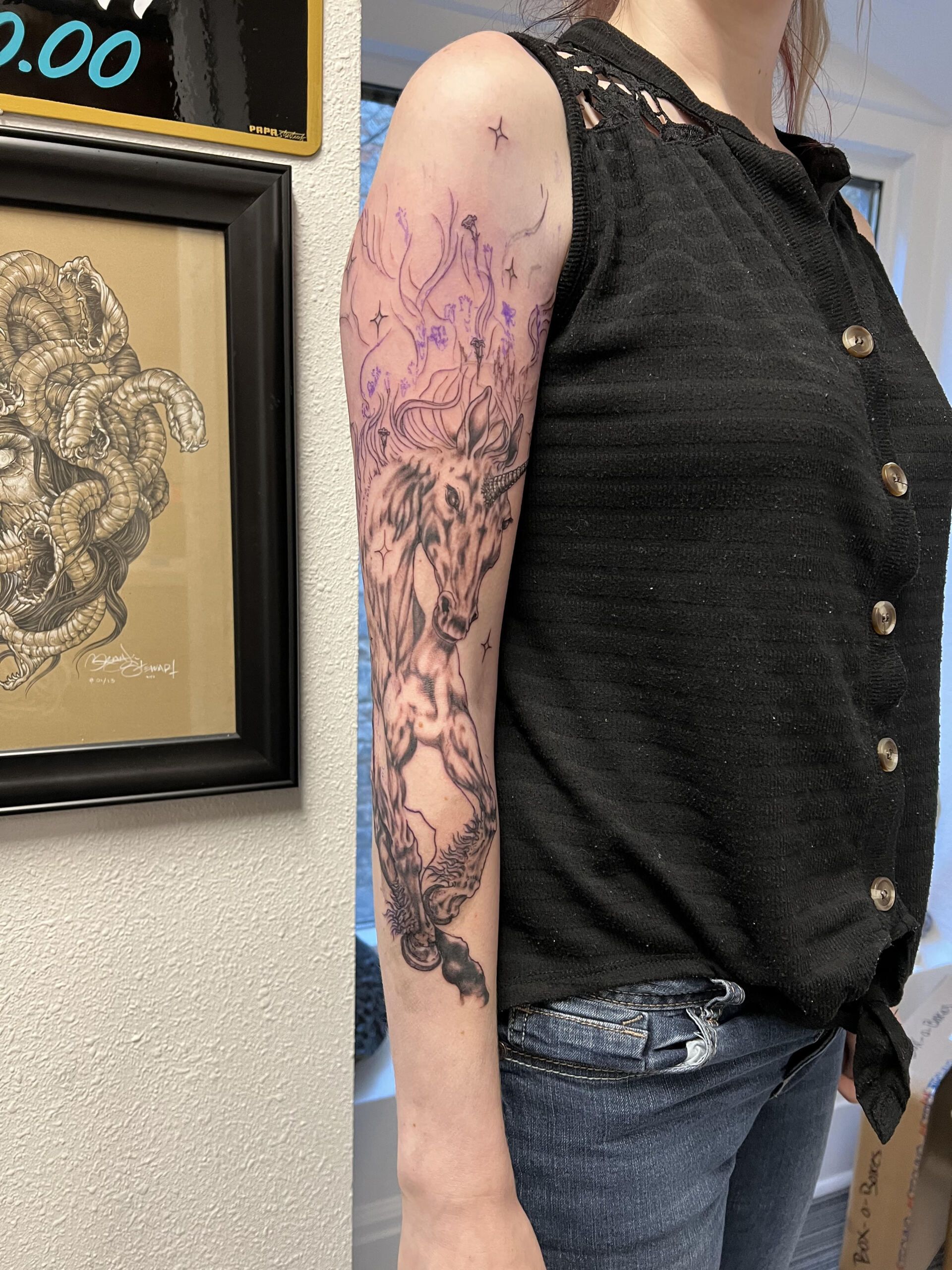 A woman with a tattoo on her arm is standing in front of a sign that says $ 0.00