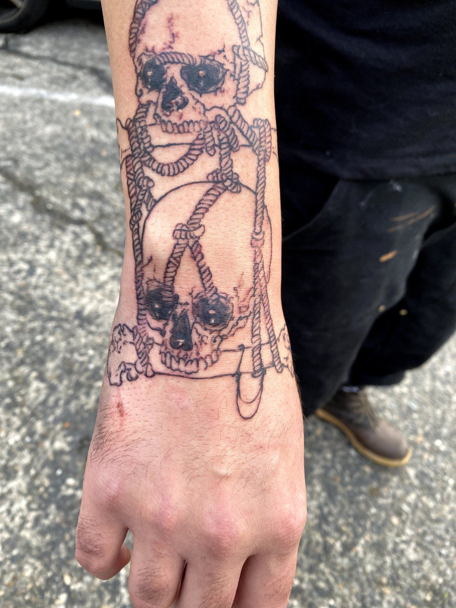 A person has a tattoo of two skulls on their wrist