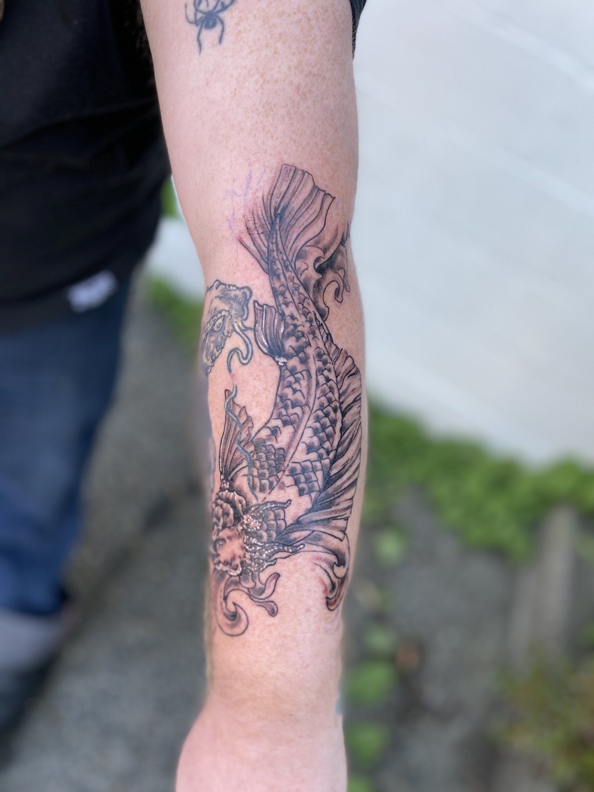 A man has a tattoo of a dragon on his forearm