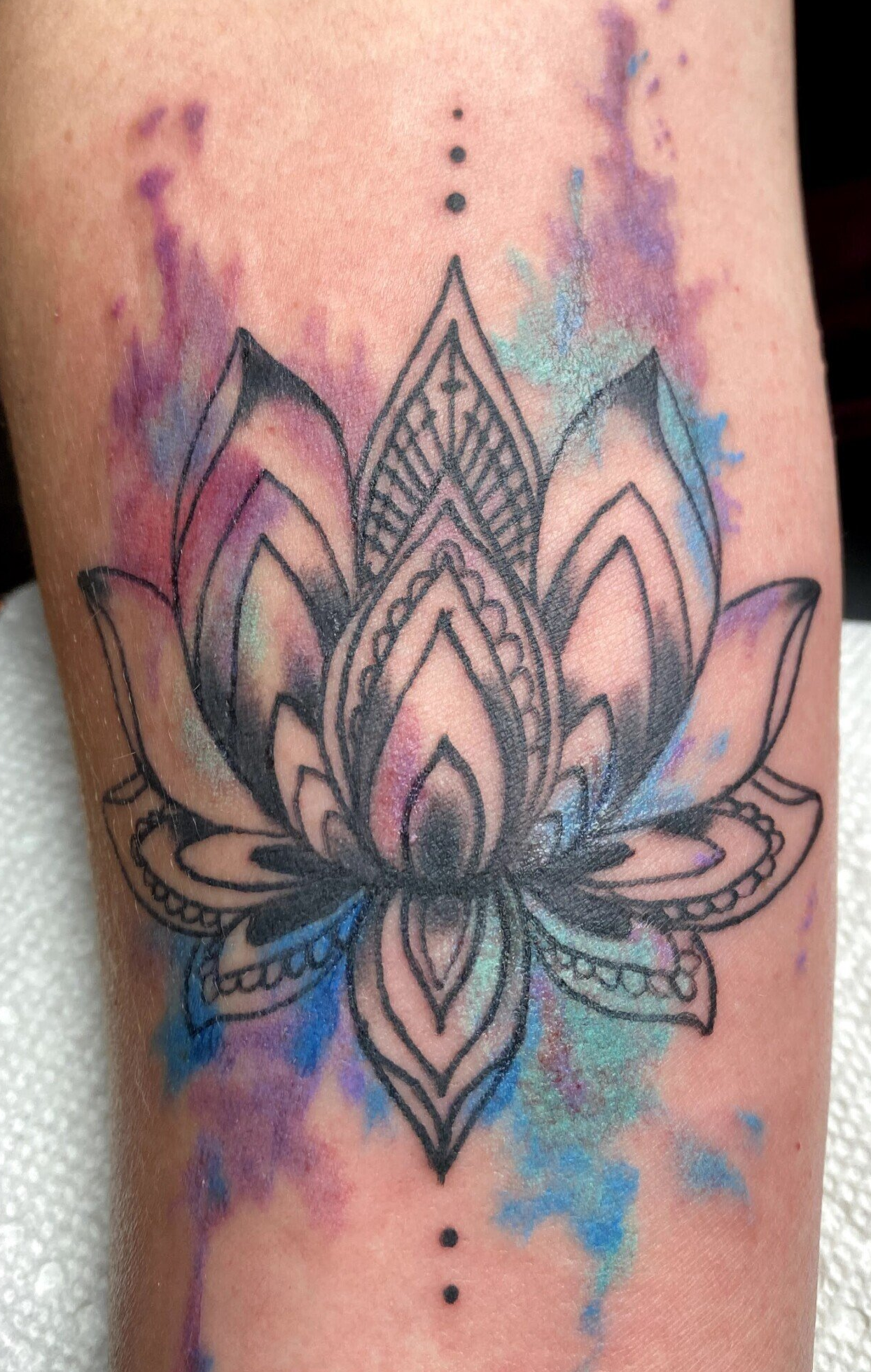 A woman has a tattoo of a lotus flower on her arm.